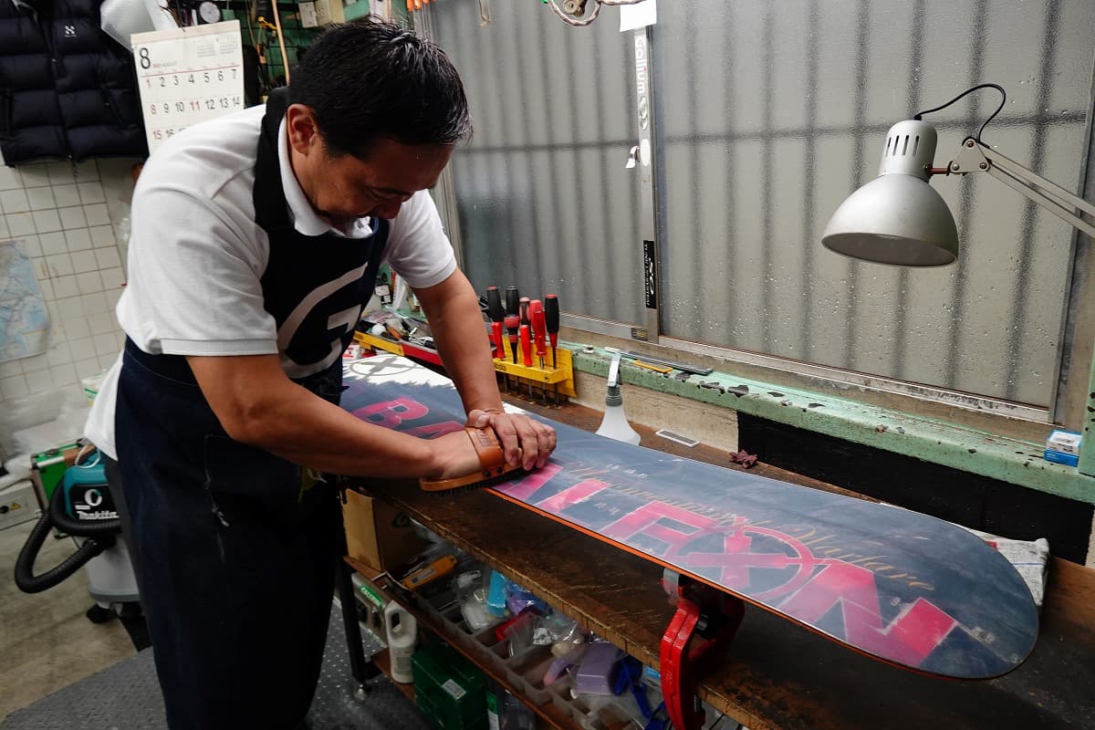 スノーボードのソールにブラシをかける坂本氏