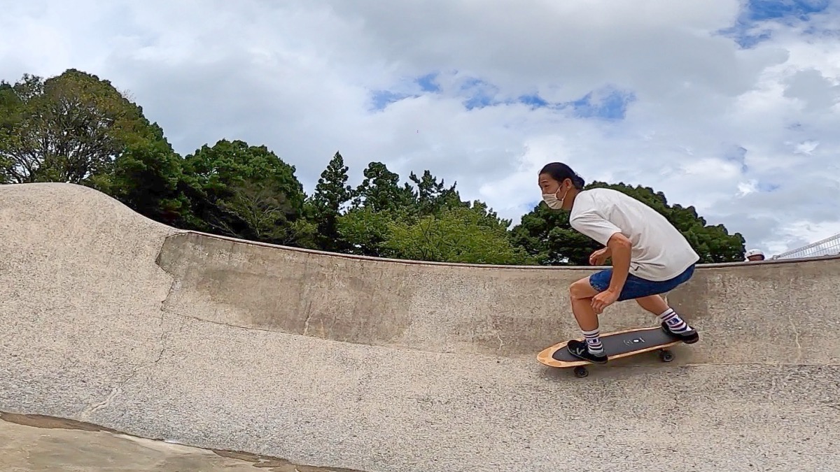 ヤウサーフスケートに乗ってスケートパークのボウルを滑るスノーボーダー