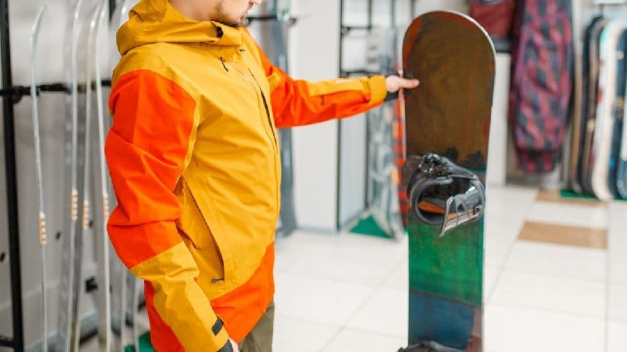 店頭でスノーボードを選ぶ男性